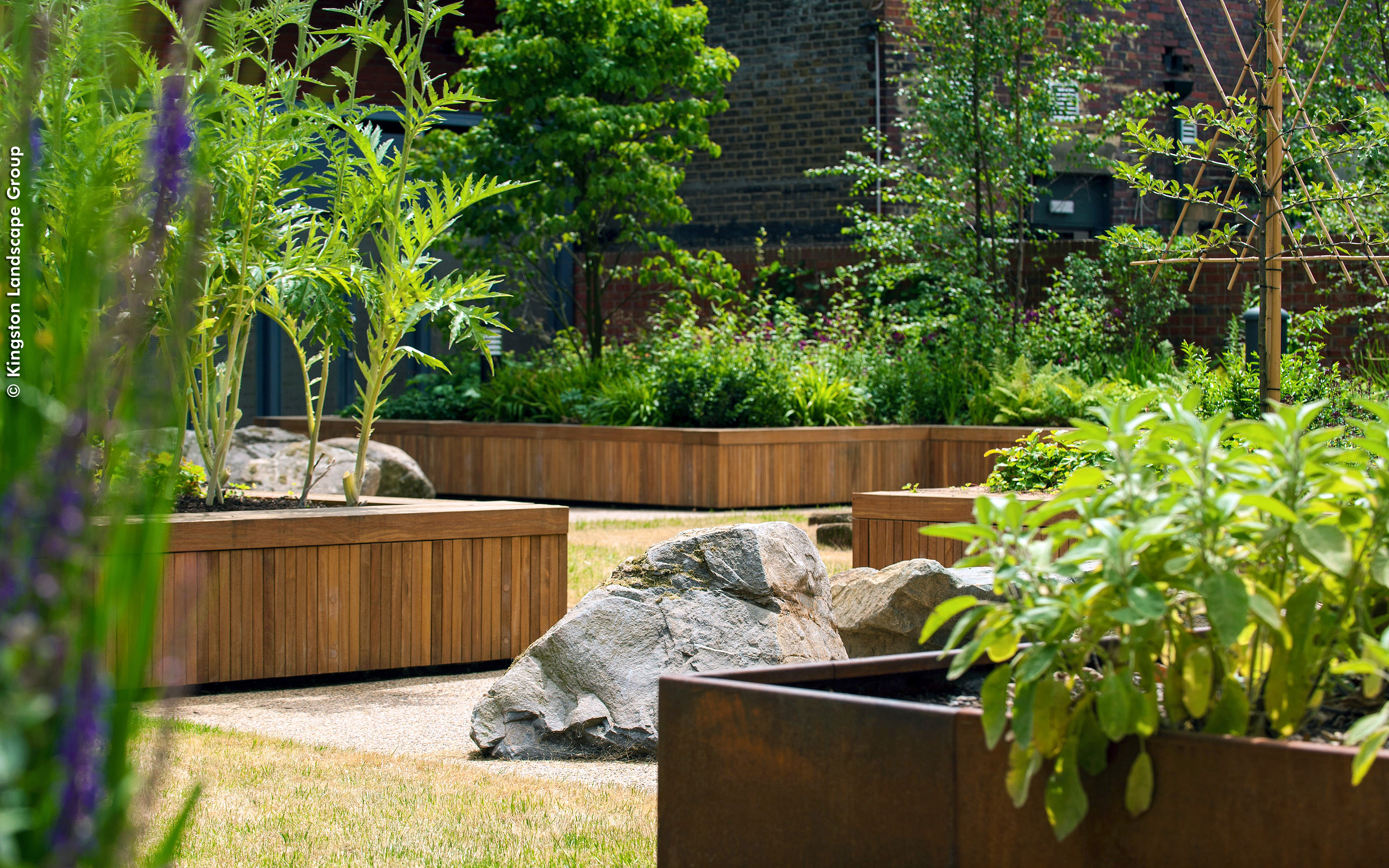 Large rocks surrounded by planters with lush greenery 