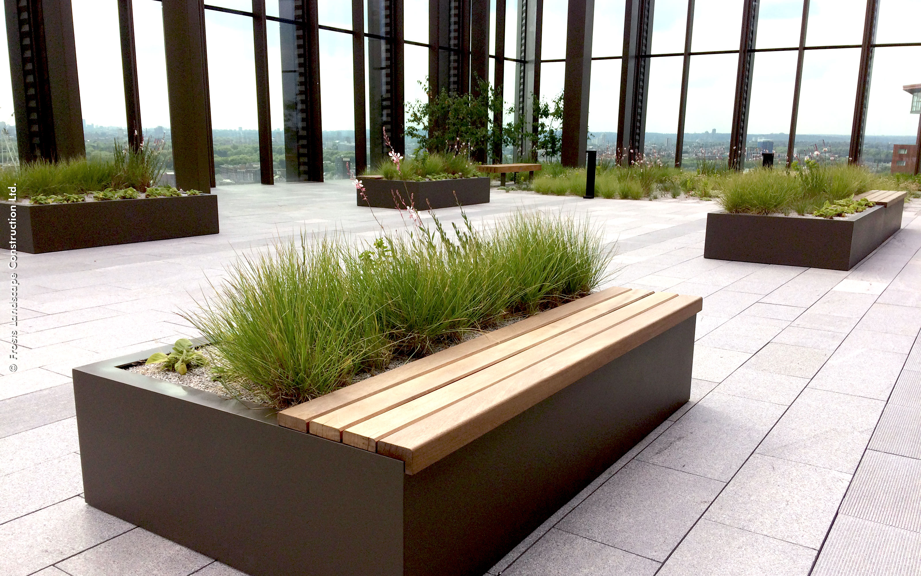 Paved roof terrace with wooden raised plant beds with seating area