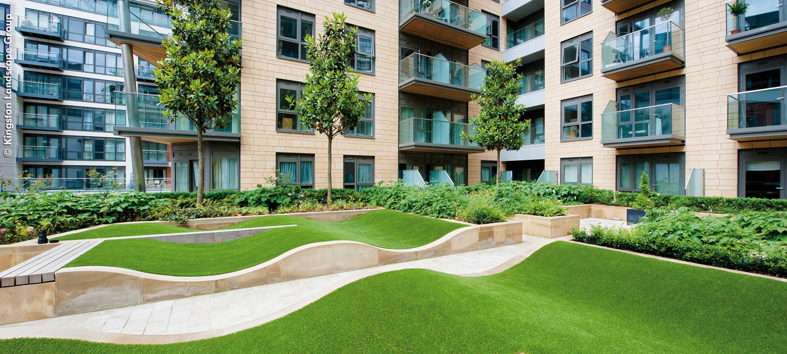 Courtyard with rolling mounds made from grass surrounded by residential blocks