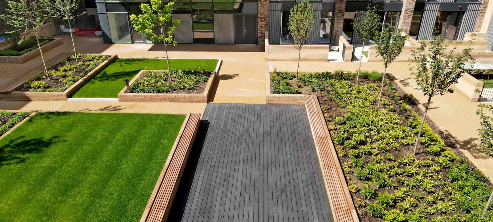 Residential courtyard with wooden benches, lawn, perennials and small trees