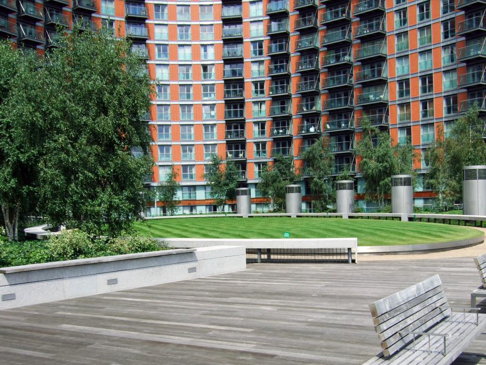 Courtyard with lawn, walkways and benches surrounded by high residential buildings