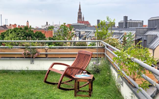 Rocking chair on a roof garden with lawn in the city